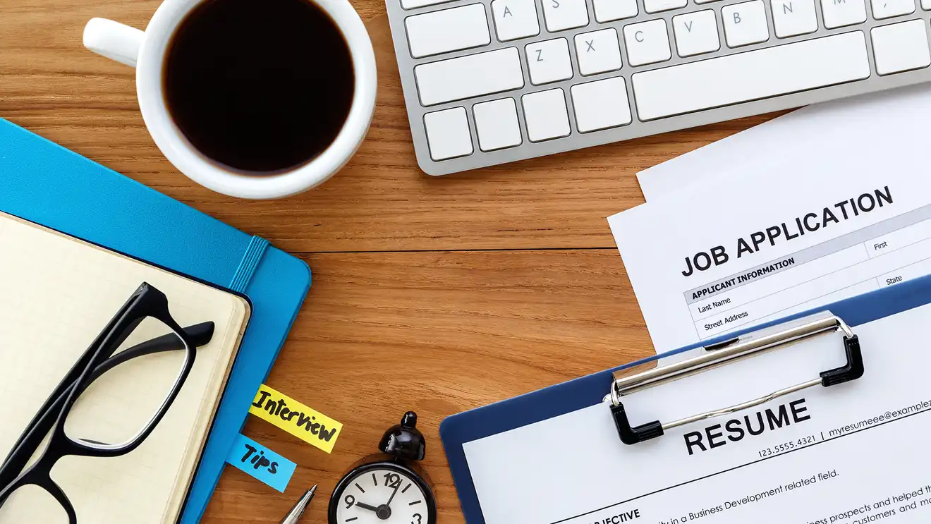 keyboard, coffee, resume and job application on a desk