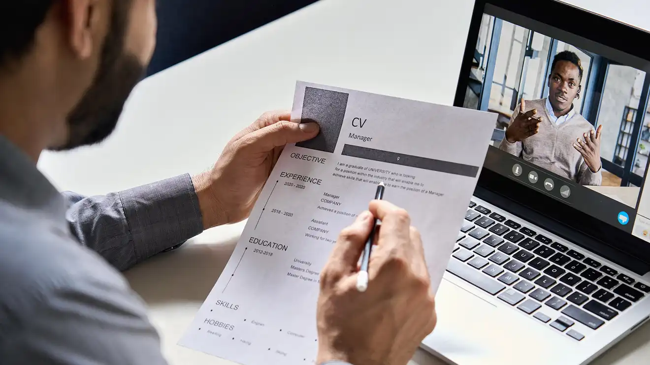 zoom interview with person reviewing resume in foreground
