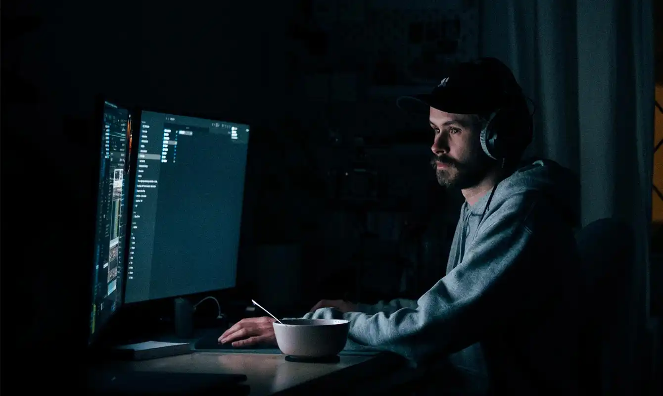 Man in dark with bowl using computer