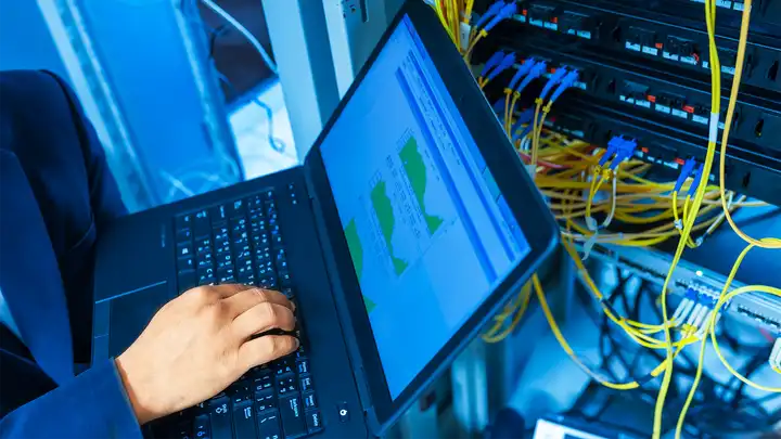 laptop open with chords for networking attached
